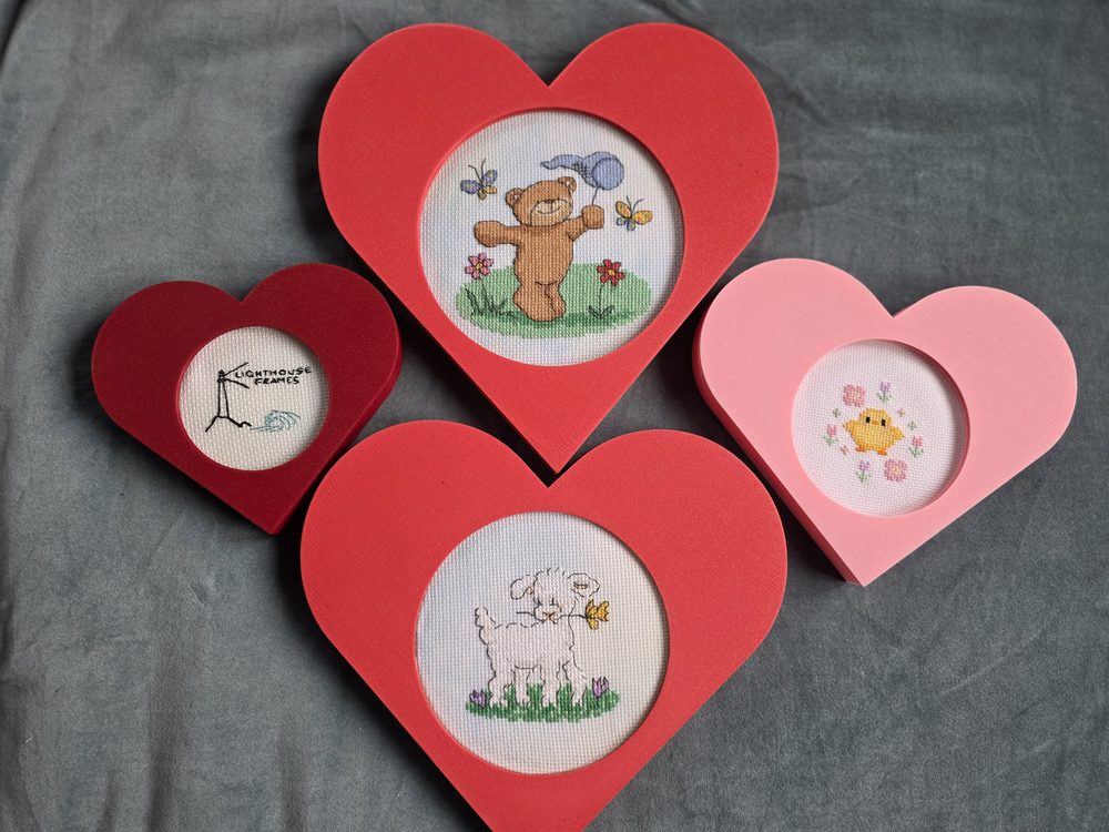 Heart-shaped cross-stitch display frames in several colors and sizes
